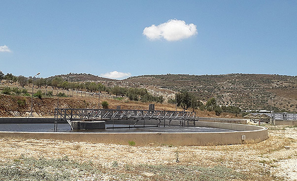 Das Foto zeigt einen Meilenstein der Partnerschaft Nablus-Nürnberg. Im Vordergrund ist das Klärbecken der Kläranlage in Nablus zu sehen, im Hintergrund Paneele der dazugehörigen Solaranlage. Beide Konstruktionen befinden sich in einer trockenen Graslandsc