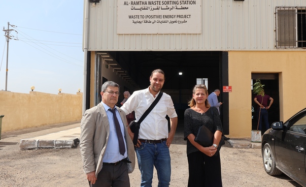 Zwei Männer und eine Frau stehen vor einer Anlage der Abfallwirtschaft in Ar-Ramtha (Jordanien)