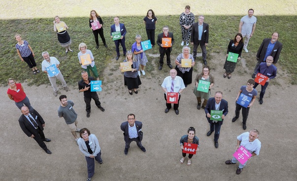Blick von oben auf eine Gruppe von Menschen, die jeweils ein Symbol der 17 globalen Nachhaltigkeitsziele halten. Foto: Engagement Global