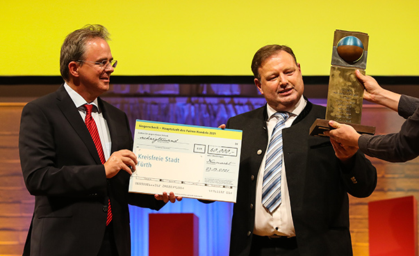 Dr. Jens Kreuter überreicht Dietmar Helm einen großen Scheck; dieser erhält von rechts noch einen Pokal.