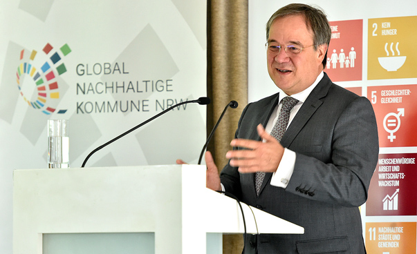 Der Ministerpräsident von Nordrhein-Westfalen, Armin Laschet, steht am Rednerpult. Im Hintergrund ist das Logo Global Nachhaltige Kommune zu sehen sowie ein Banner mit den 17 globalen Nachhaltigkeitszielen.