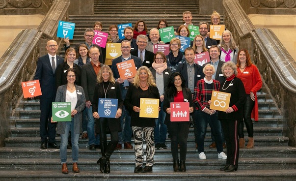 Gruppenfoto auf einer Treppe mit den Symbolen der globalen Nachhaltigkeitsziele.