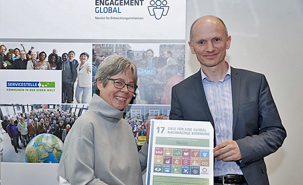 Eine Frau und ein Mann halten ein Dokument, das die Symbole der nachhaltigen Entwicklungsziele zeigt. Foto:JoHempelPhotography