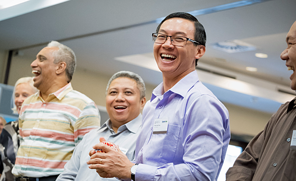 Mehrere Teilnehmende aus Vietnam, Indonesien, Sri Lanka und Deutschland stehen bei der Abschlussrunde der Konferenz herzlich lachend zusammen. Foto: Martin Magunia
