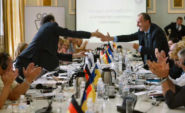 Zwei Männer reichen sich beim ersten Runden Tisch Deutschland-Ukraine 2016 über einen Tisch die Hände.