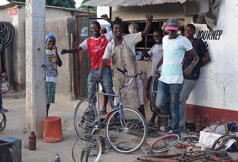 Quelques jeunes hommes se tiennent de bonne humeur devant un magasin de vélos.