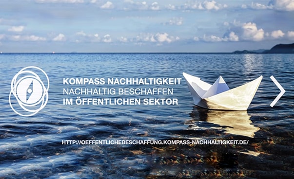 Rechts auf dem Bild ist ein Papierschiffchen auf einem Gewässer zu sehen; links unter anderem der Schriftzug "Kompass Nachhaltigkeit"
