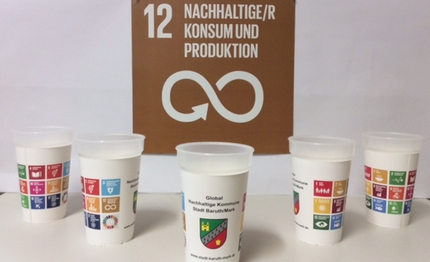 Fünf Becher mit den Symbolen der 17 globalen Nachhaltigkeitsziele stehen vor einem großen Icon des Nachhaltigkeitsziels 12 - Nachhaltiger Konsum.