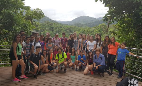 Gruppenfoto der Schülerinnen und Schüler. Im Hintergrund ist ein tropischer Wald zu sehen.