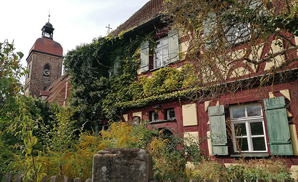Ein Fachwerkhaus im fränkischen Roßtal, hinter dem Haus ist eine Kirchturmspitze zu sehen.