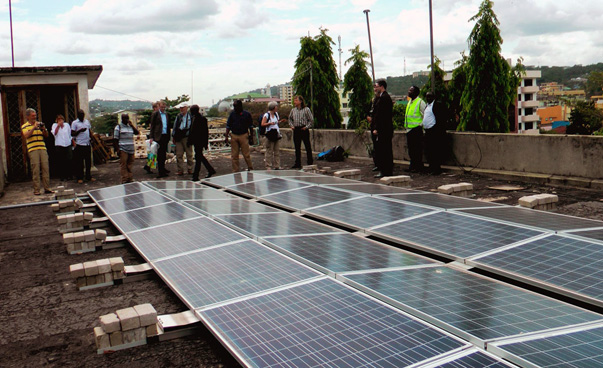 Eine Gruppe von Menschen besichtigt eine Photovoltaik-Anlage auf dem Dach eines Gebäudes.