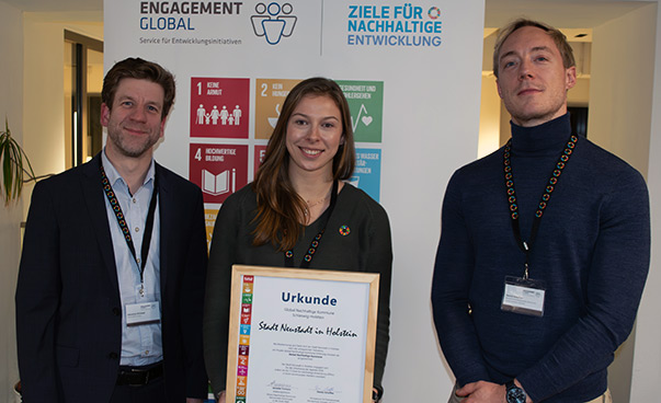 Übergabe der Urkunde von Sebastian Ohlmeyer (SKEW) und Dennis Scheffler (Mekun) zur Teilnahme an dem Projekt „Global Nachhaltige Kommune" stellvertretend an Lina Koop.