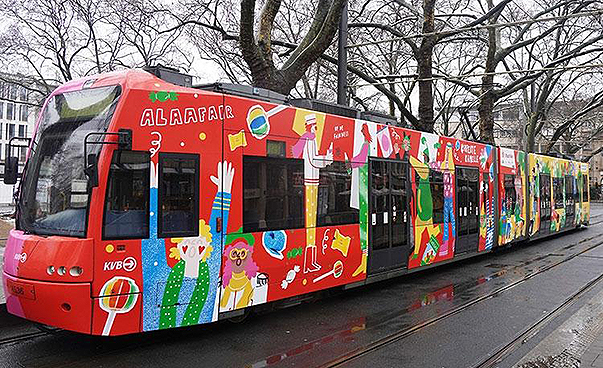 Eine bunt bemalte Straßenbahn mit Karnevalsmotiven fährt durch Köln