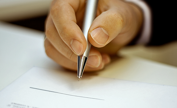 Eine Hand hält einen Kugelschreiber über einem Blatt Papier. Foto: Jörg Schmalenberger