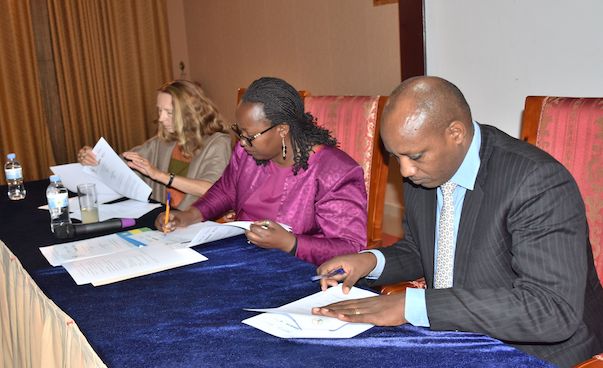 Zwei Frauen und ein Mann unterzeichnen einen Vertrag, Foto: Minaloc Rwanda