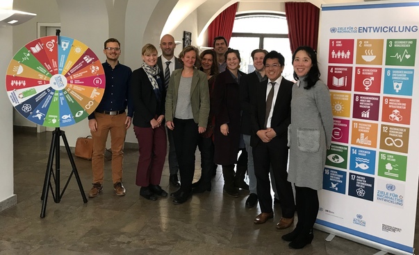 Group photo of the participants. Next to them a poster and a wheel of fortune with the pictograms of the Sustainable Development Goals. Photo: Engagement Global