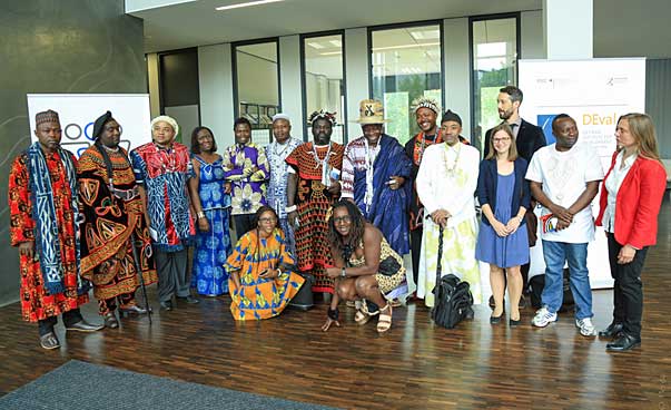 Eine Gruppe steht nebeneinander, einige Personen tragen traditionelle afrikanische, andere europäische Kleidung. Foto: Perez