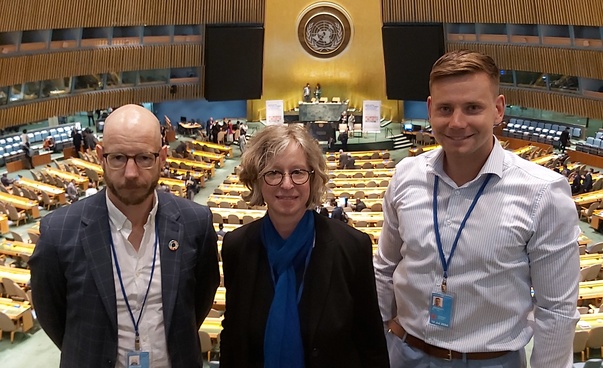 Zwei Männer und eine Frau im Plenarsaal der Vereinten Nationen.