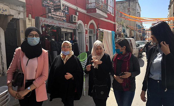 Fünf Frauen unterhalten sich im Gehen in einem historischen Stadtviertel.