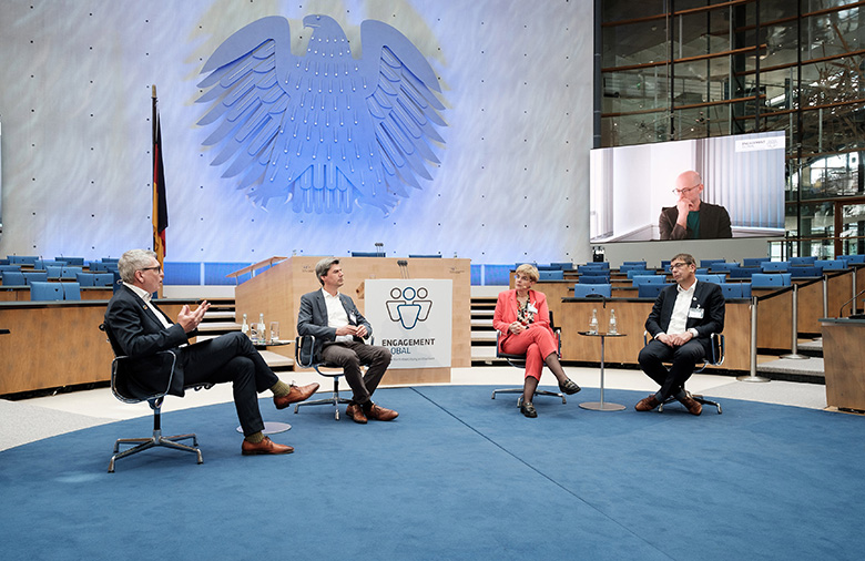 Drei Männer und eine Frau im Zentrum des Plenarsaals des ehemaligen Bundestags.