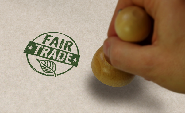Mit einem Stempel wird der Schriftzug "Fair Trade" auf ein Blatt gedruckt.