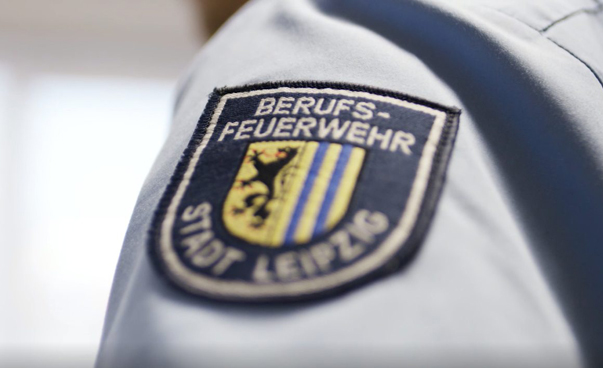 Ein Aufnäher auf einer blauen Uniform ist zu sehen; darauf steht: Berufsfeuerwehr Stadt Leipzig