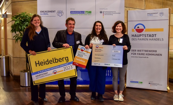 Die ausgezeichnete Stadt Heidelberg wurde durch 4 Mitarbeiter*innen repräsentiert, die ihre Urkunde, ihr Ortsschild und ihren Scheck herzeigen.