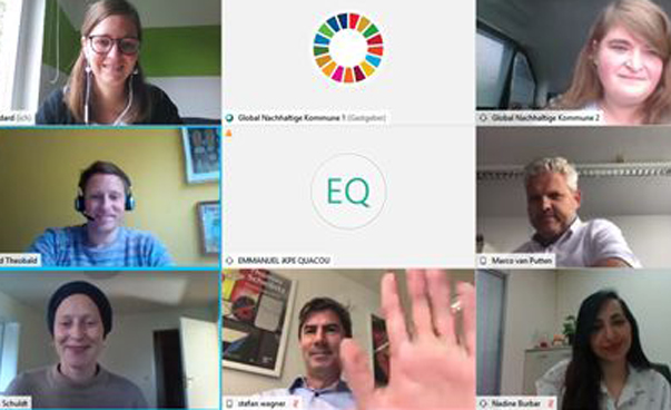 Ein Screenshot zeigt mehrere Personen einer Online-Konferenz; in der Mitte oben ist das globale Nachhaltigkeitssymbol zu sehen.