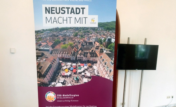 Auf einem Plakat, dass eine Stadt von oben zeigt, steht "Neustadt macht mit" geschrieben.