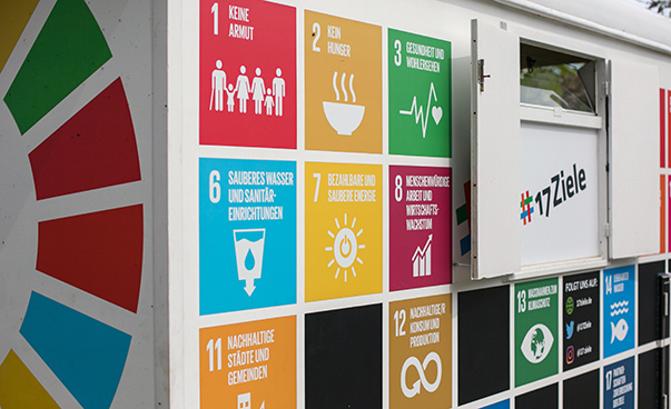 Übersicht über die 17 globalen Nachhaltigkeitsziele der Vereinten Nationen in Form bunter Kacheln auf einem Wagen.