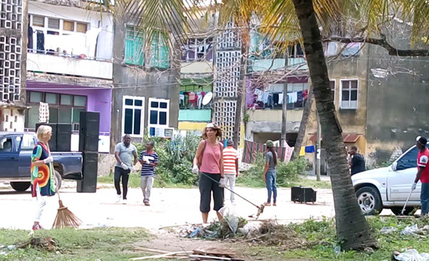 Some people are cleaning a street; buildings can be seen in the background.