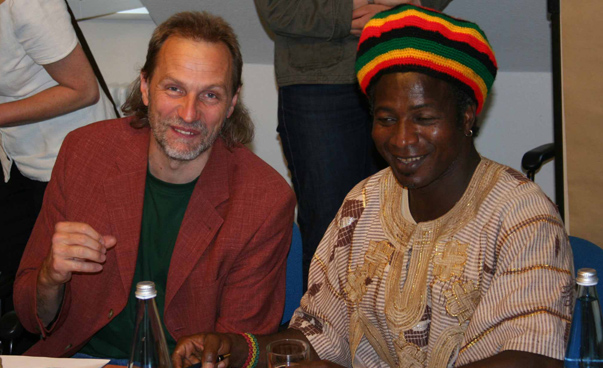 Ein europäisch aussehnder Mann und eine afrikanisch aussehende Frau sitzen nebeneinander.