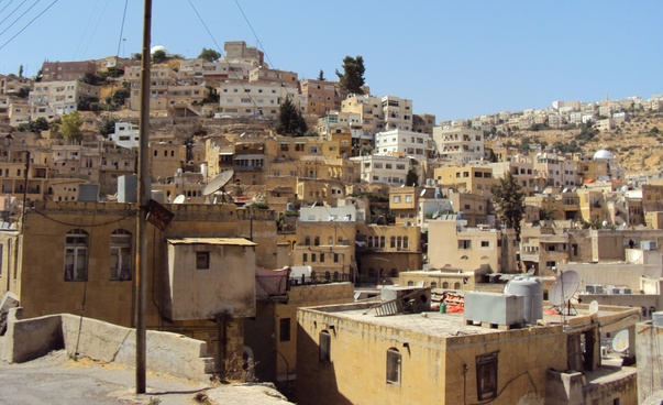 Blick auf eine jordanische Stadt. Dichte Bebauung erstreckt sich über mehrere Hügel.