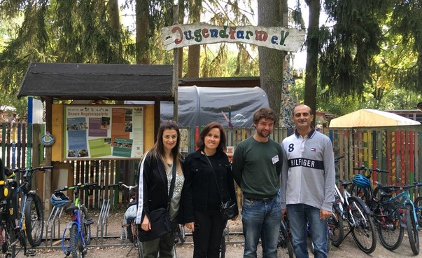 Two women and two men are standing in front of the entrance to the youth farm in Erlangen.