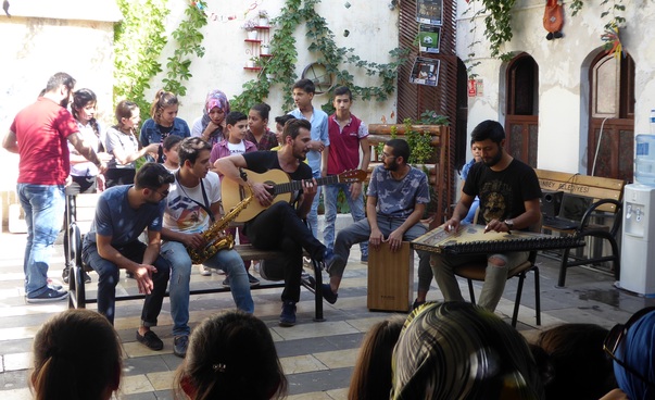 Several people making music together in a courtyard. Photo: Engagement Global