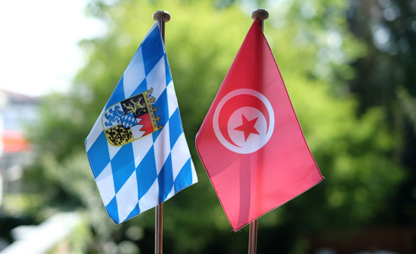 Bayerische und tunesische Flagge vor grünem Hintergrund.