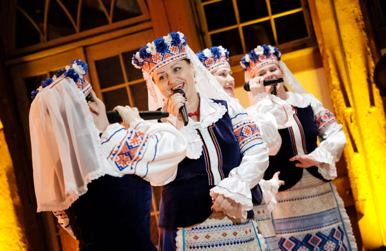 Frauen in tradidionellen Kleidern singen und tanzen.