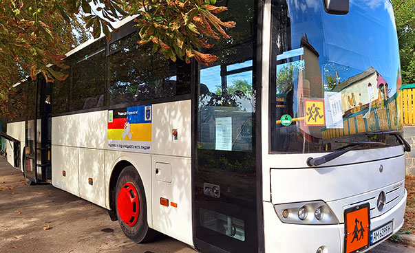 The photo shows a white bus with writing in German and Ukrainian.