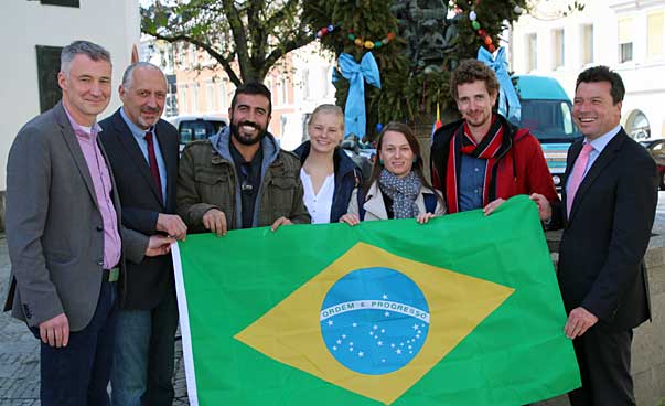 Eine Gruppe hält eine brasilianische Fahne in Händen und lächelt in Richtung des Fotografen.