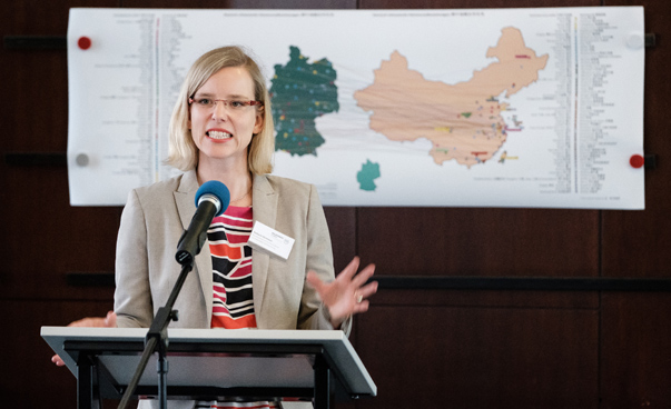 Stefanie Sörensen steht hinter einem Rednerpult und spricht in das Mikrofon. Im Hintergrund ist eine Karte der partnerschaftlichen Verbindungen zwischen deutschen und chinesischen Kommunen zu sehen.