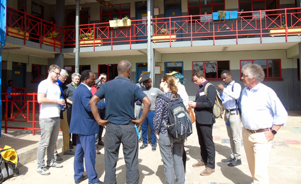 Several people stand in a circle in front of a building and talk.