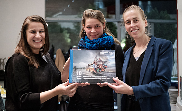 Ana Druga, Designerin, Helena Jansen, Vertreterin der Siegerkommune, und Marie Mevellec von der SKEW halten gemeinsam und lächelnd den Bildband in die Kamera.