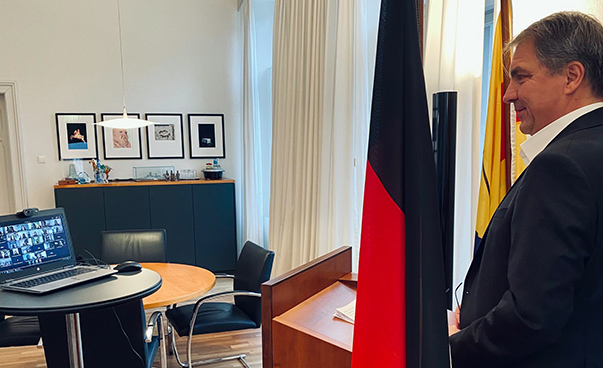 Der Oldenburger Oberbürgermeister Jürgen Krogmann steht an einem Pult zwischen zwei Deutschlandflaggen und spricht in Richtung eines vor ihm stehenden Laptops.