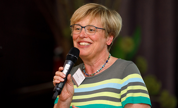 Barbara Baumbach vom Bundesministerium für wirtschaftliche Zusammenarbeit und Entwicklung hält lachend ein Mikrofon in der Hand.