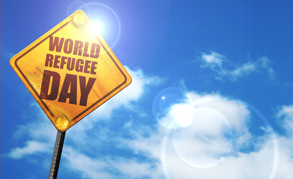 Ein gelbes Schild mit der Aufschrift World Refugee Day glänzt in der Sonne. Foto: panthermedia.net